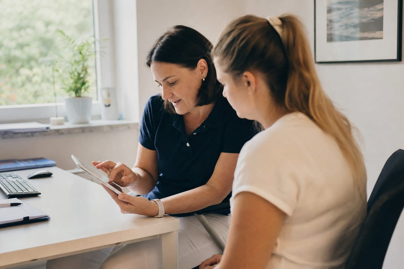 Betriebsinhaber und neue Fachkraft am Tablet in der Werkstatt